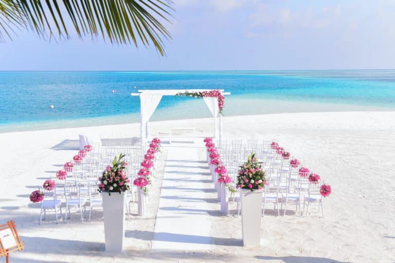 Beach wedding by Sophé Events featuring white sand and elegantly arranged white chairs.